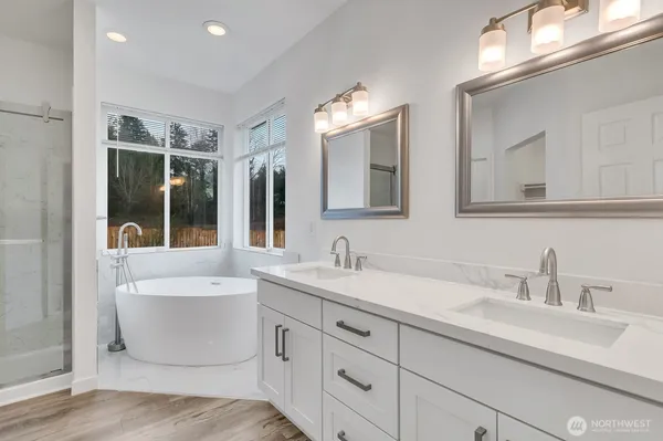 a bathroom with a double vanity sink mirror and bathtub