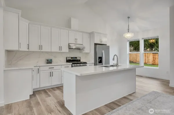 a kitchen with stainless steel appliances granite countertop a stove a sink a refrigerator and white cabinets with wooden floor