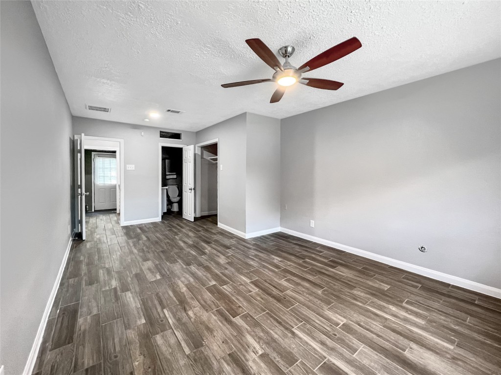6347 Limestone Street Houston, TX 77092 - Photo 12 of 26 Discover the serenity of this spacious primary bedroom, featuring elegant wood-style flooring, ample natural light, and a sleek ceiling fan—your perfect retreat.