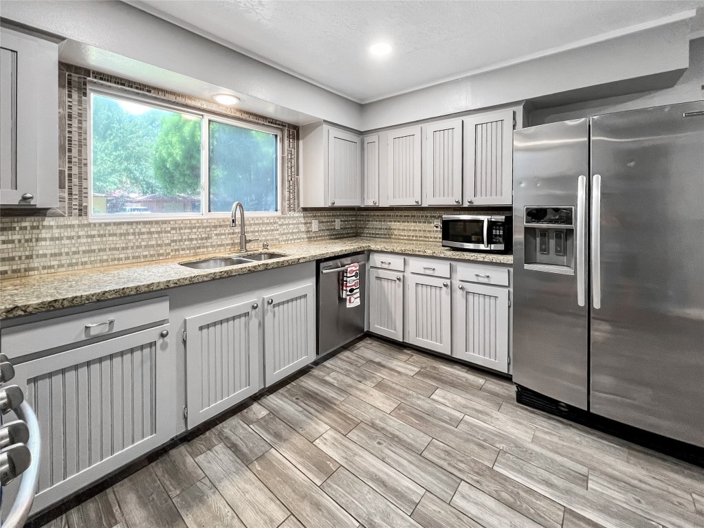 6347 Limestone Street Houston, TX 77092 - Photo 3 of 26 This inviting kitchen boasts sleek stainless steel appliances, elegant granite countertops, and ample natural light through a large window, offering a perfect blend of style and functionality.