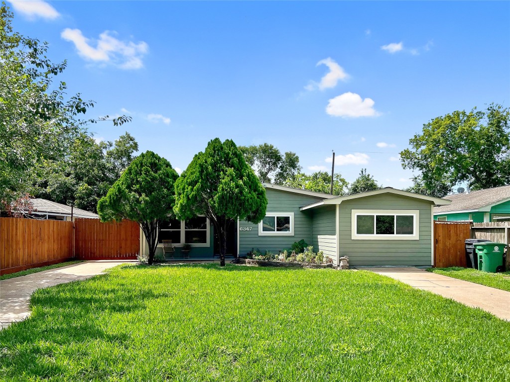 6347 Limestone Street Houston, TX 77092 - Photo 4 of 26 Charming single-story home with a manicured lawn, mature trees, and a welcoming facade. Features a wooden fence, a paved driveway, and plenty of greenery, offering privacy and curb appeal.