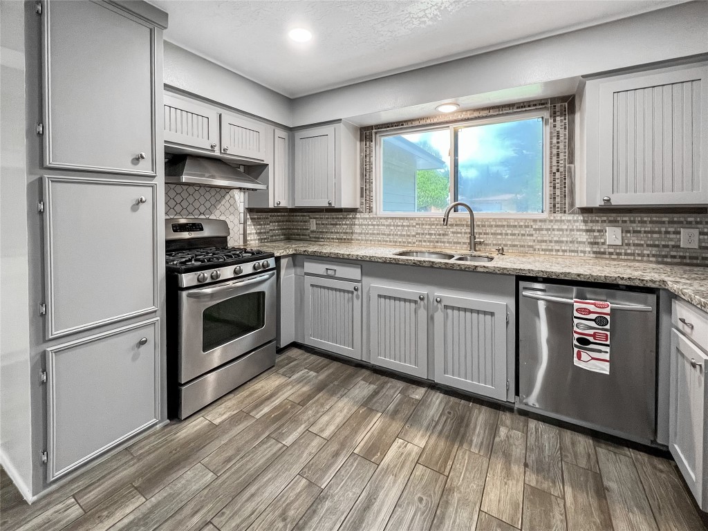 6347 Limestone Street Houston, TX 77092 - Photo 7 of 26 This modern kitchen boasts sleek stainless steel appliances, elegant granite countertops, and a stylish tile backsplash, all beautifully illuminated by natural light through a generous window.