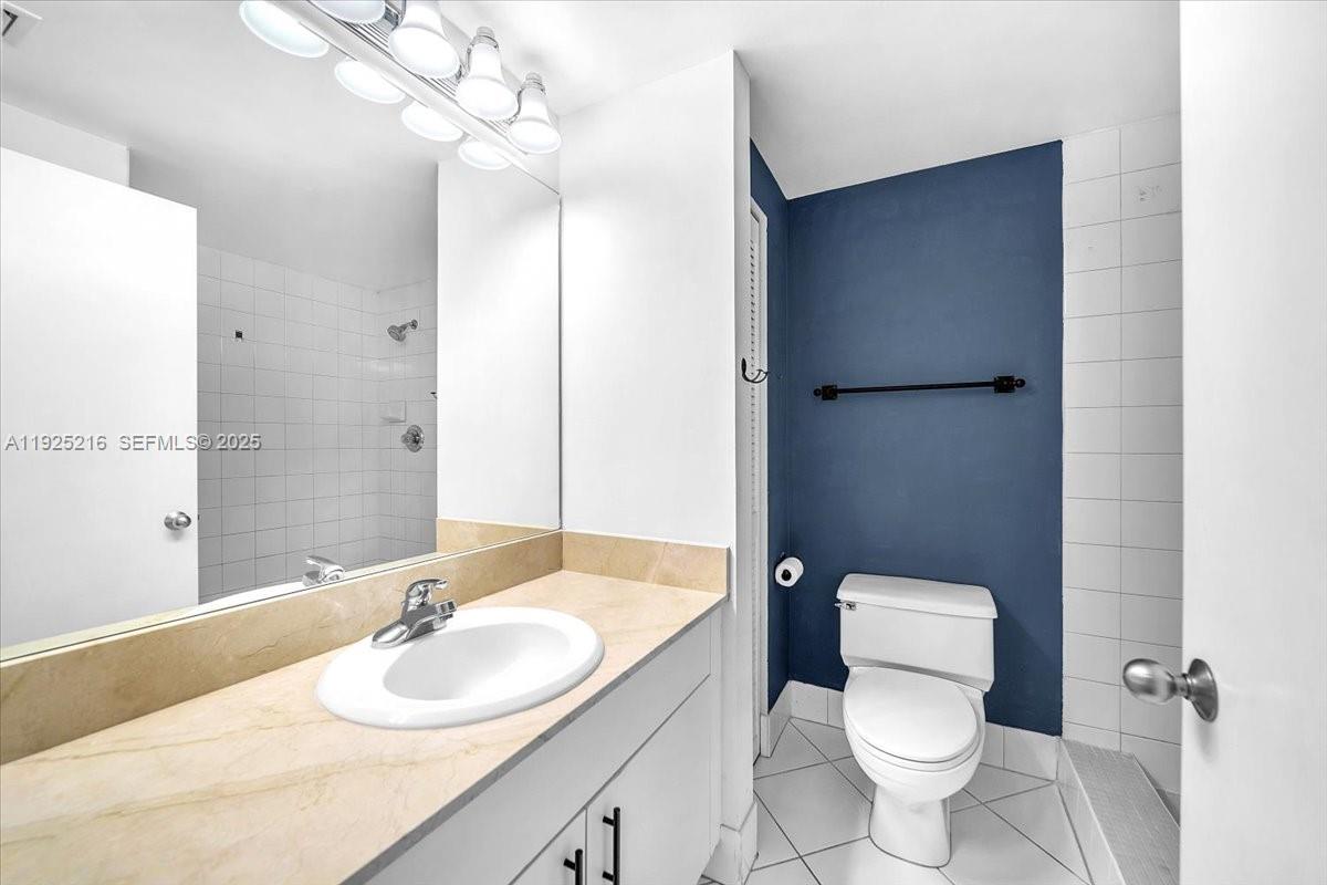 701 Brickell Key Boulevard, Unit 1911 Miami, FL 33131 - Photo 25 of 39 a bathroom with a granite countertop sink toilet a mirror and a shower