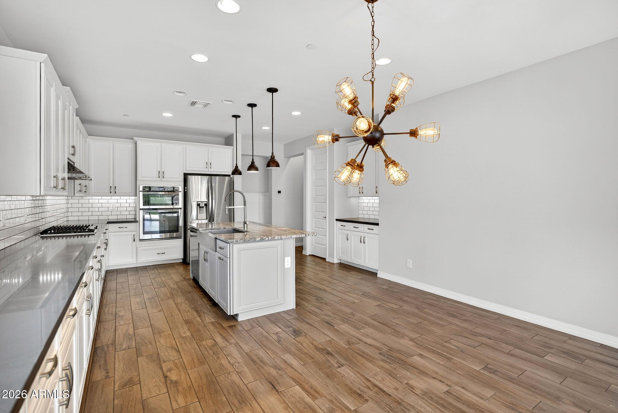 12124 West Peak View Road Peoria, AZ 85383 - Photo 9 of 38 an open kitchen with wooden floor and stainless steel appliances
