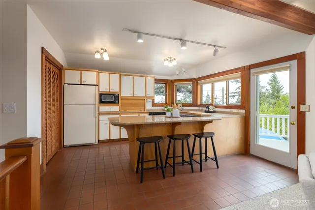 a kitchen with stainless steel appliances granite countertop a refrigerator a sink dishwasher a dining table and chairs with wooden floor