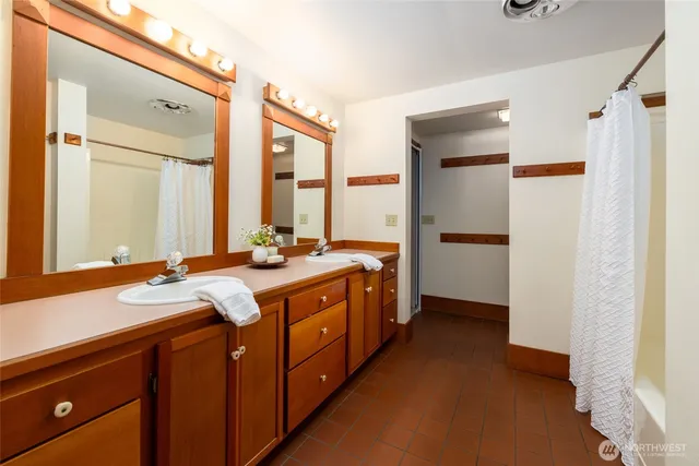 a spacious bathroom with a double vanity sink a mirror and a shower