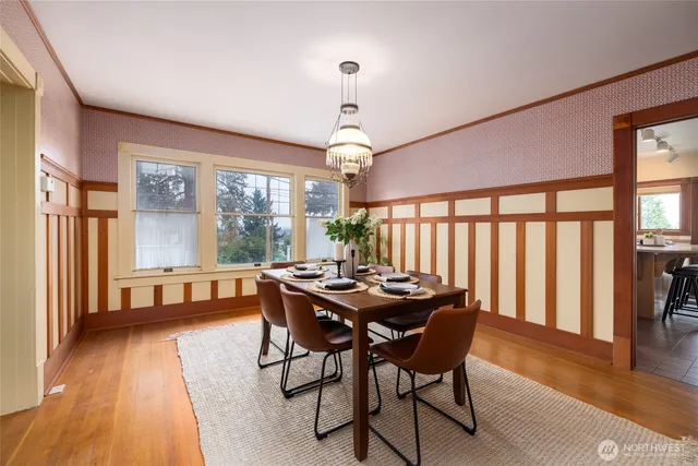 a dining room with wooden floor a chandelier a wooden table and chairs