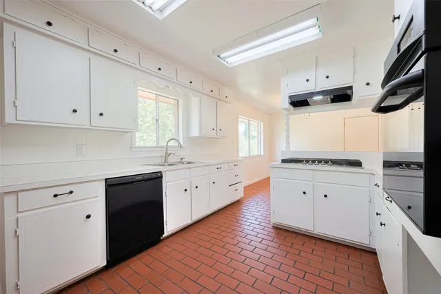 a kitchen with granite countertop white cabinets white appliances with a sink and dishwasher