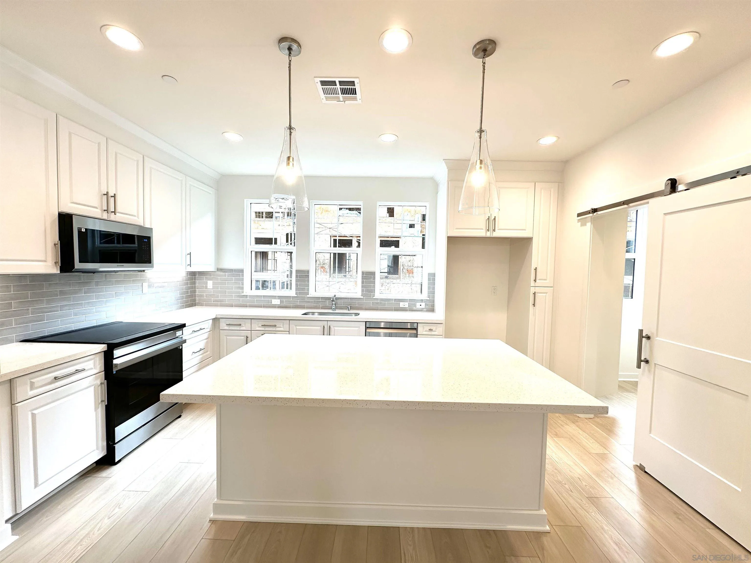 2511 Chamomile Lane Carlsbad, CA 92008 - Photo 16 of 51 a large kitchen with stainless steel appliances kitchen island granite countertop a sink a stove and a wooden floors