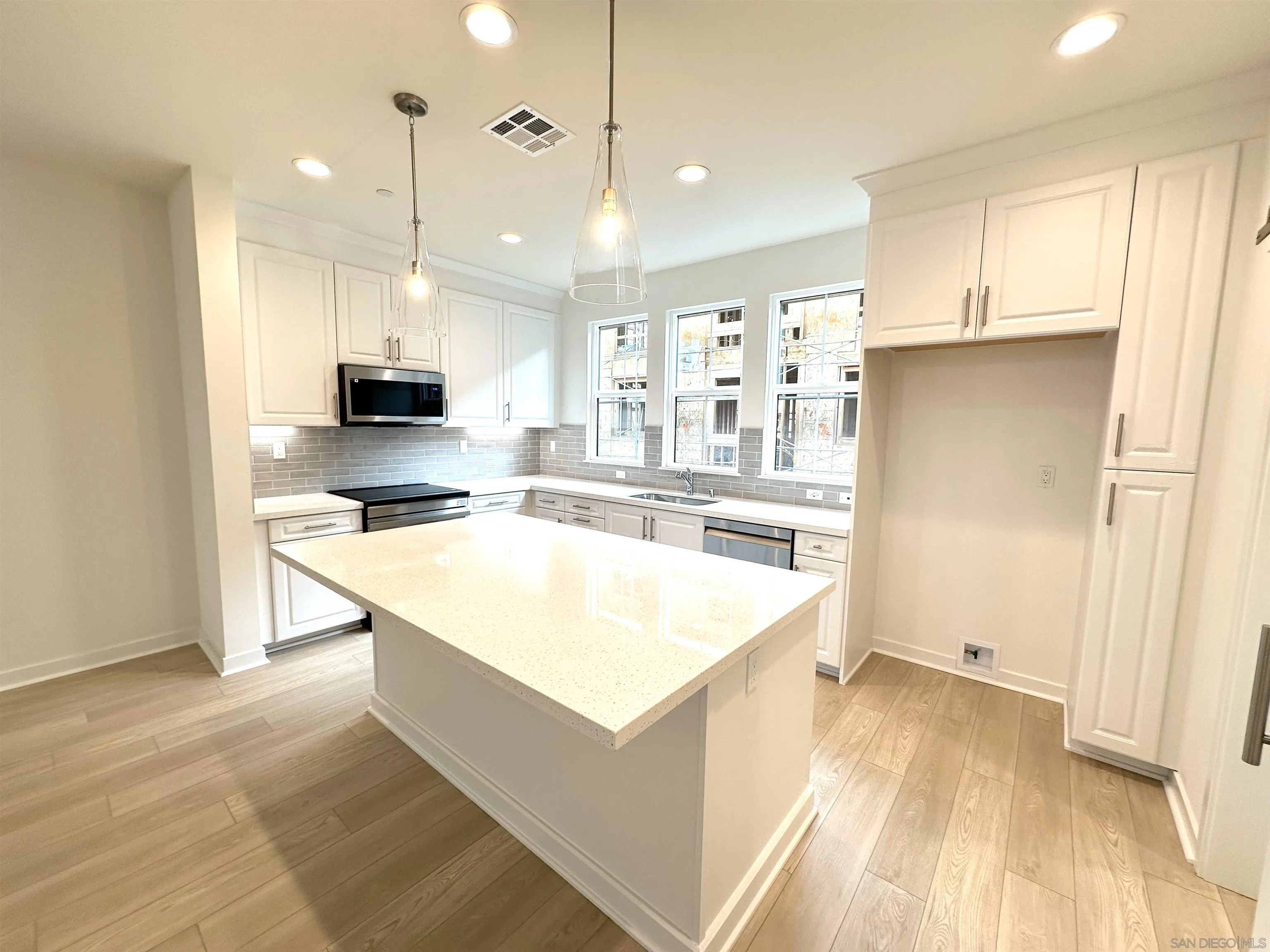 2511 Chamomile Lane Carlsbad, CA 92008 - Photo 18 of 51 a large kitchen with kitchen island a stove a sink a refrigerator and white cabinets with wooden floor