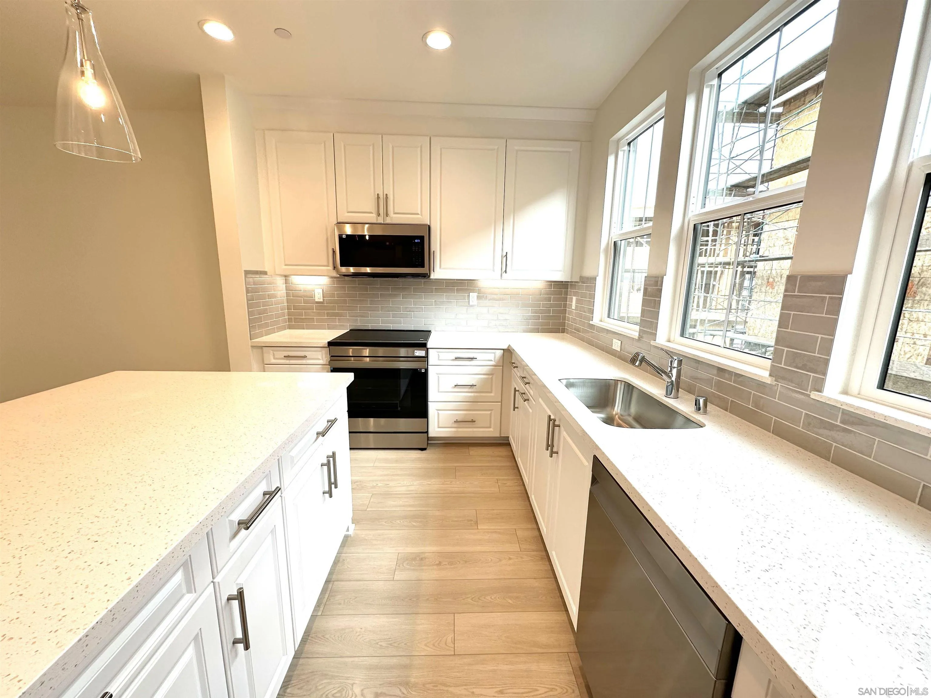 2511 Chamomile Lane Carlsbad, CA 92008 - Photo 3 of 51 a kitchen with stainless steel appliances granite countertop a sink a stove top oven a refrigerator with white cabinets and wooden floor