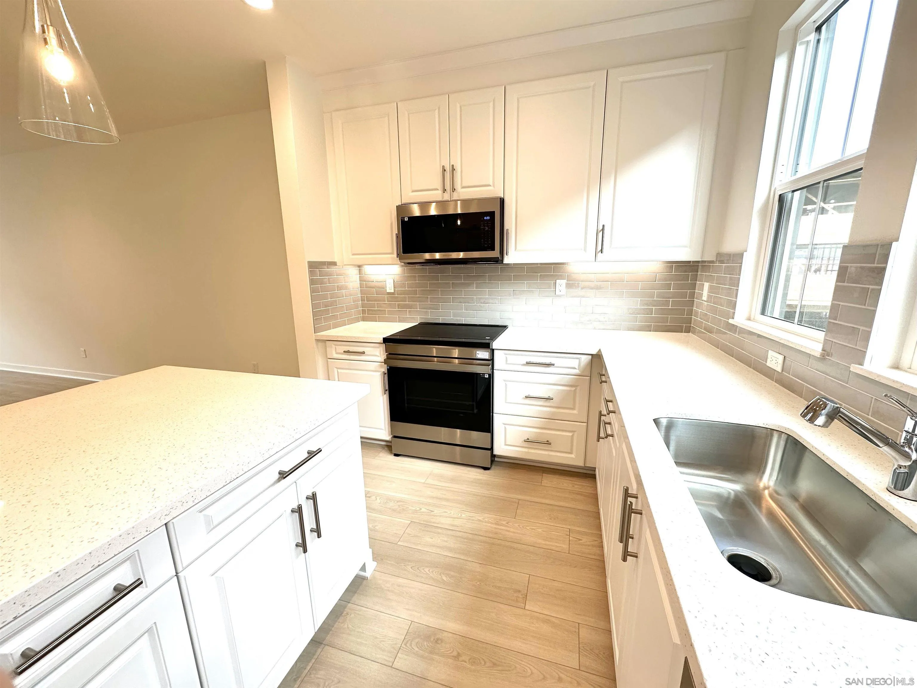 2511 Chamomile Lane Carlsbad, CA 92008 - Photo 7 of 51 a kitchen with granite countertop a sink and a stove top oven with wooden floor