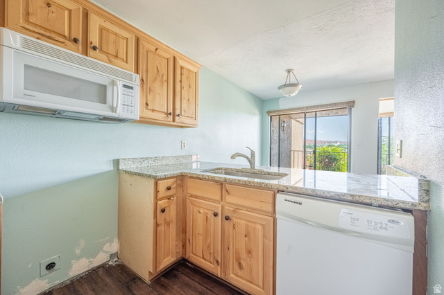 161 West 950 South, Unit C5 St. George, UT 84770 - Photo 7 of 14 Kitchen featuring wood-finish cabinetry, light-toned granite-style countertops, an undermount sink with a chrome faucet, a built-in microwave, and a white dishwasher