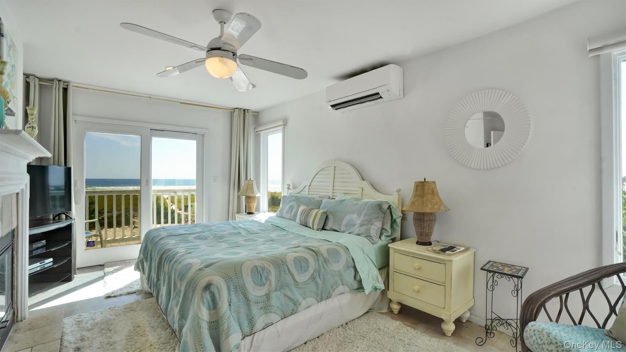 431 Dune Road Westhampton Beach, NY 11978 - Photo 15 of 27 a spacious bedroom with a bed a chandelier and a flat tv