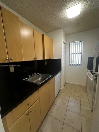 a kitchen with granite countertop stainless steel appliances a sink stove and cabinets