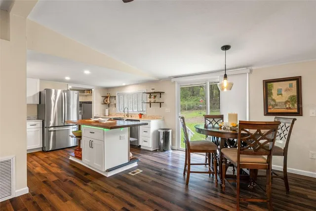 a kitchen with stainless steel appliances a stove a sink dishwasher a refrigerator and white cabinets with wooden floor