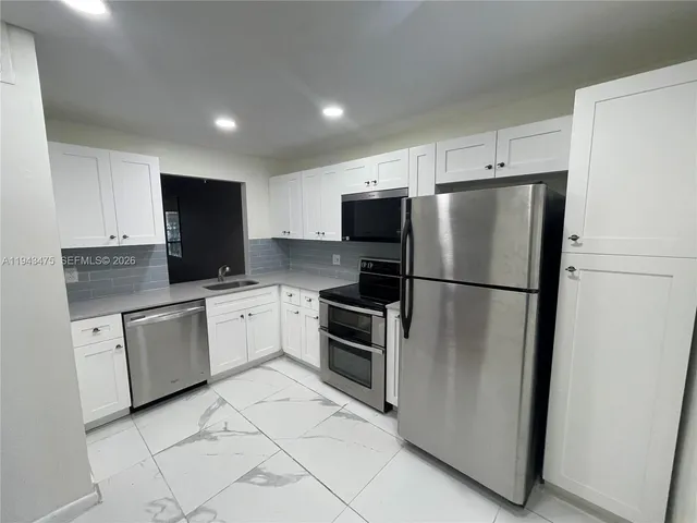 a kitchen with stainless steel appliances a refrigerator sink and microwave