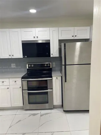 a view of kitchen with stainless steel appliances and refrigerator
