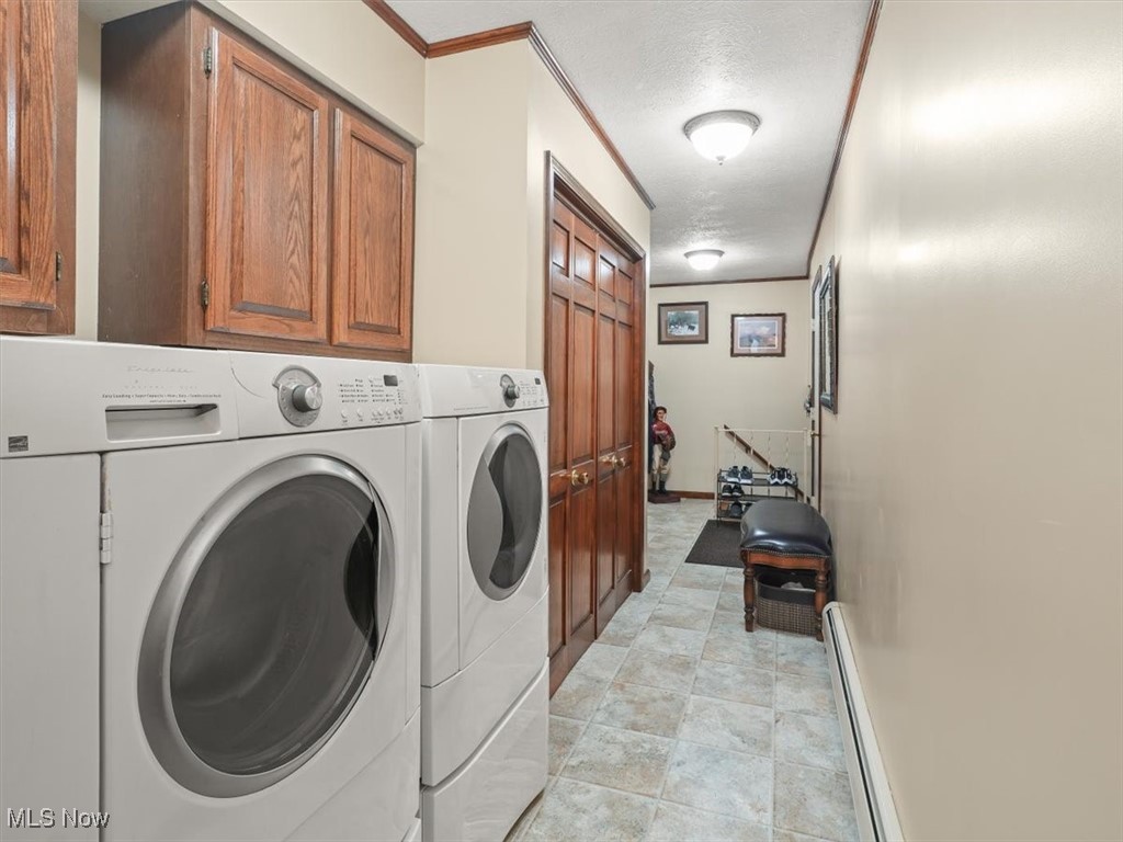 Laundry room featuring independent washer and dryer, a textured ceiling, crown molding, and cabinets