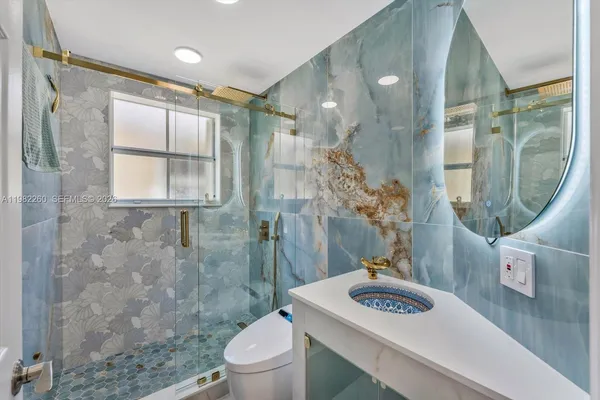 a bathroom with a granite countertop sink a toilet and shower