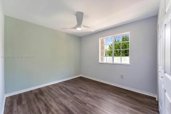 an empty room with wooden floor chandelier and windows