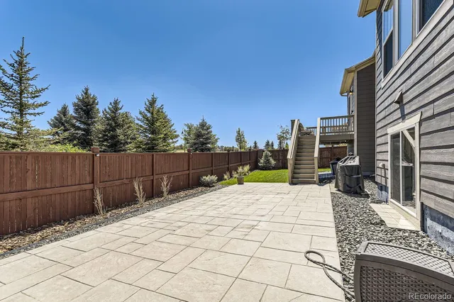 a view of backyard with large trees and wooden fence