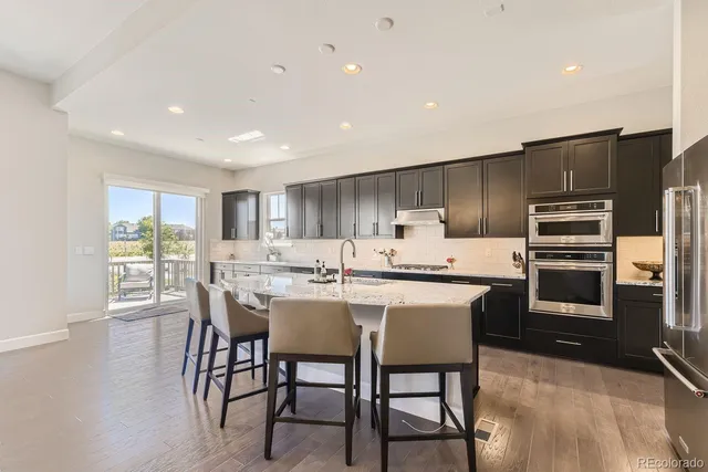 a kitchen with kitchen island a dining table chairs stainless steel appliances and cabinets