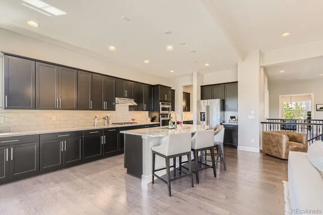 a kitchen with stainless steel appliances granite countertop a table chairs sink and cabinets