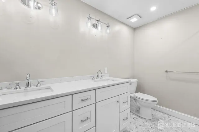 a bathroom with a granite countertop sink a toilet and a mirror