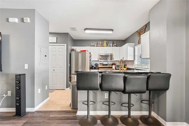 a kitchen with granite countertop a dining table chairs cabinets and stainless steel appliances