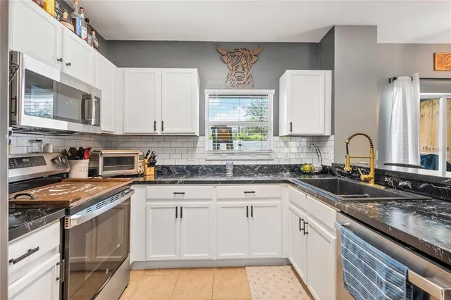 a kitchen with granite countertop a sink stainless steel appliances and cabinets