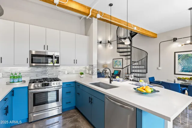 a kitchen that has a lot of white cabinets and stainless steel appliances
