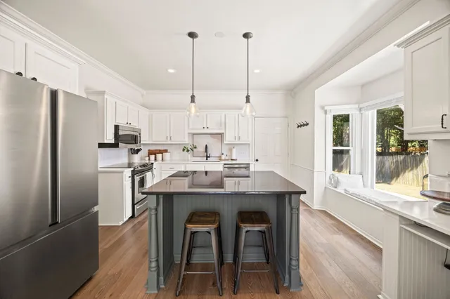 a kitchen with refrigerator a sink and chairs