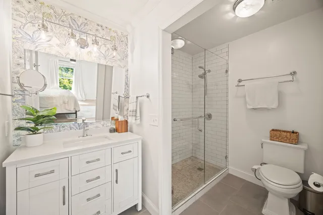 a bathroom with a shower sink vanity mirror and toilet