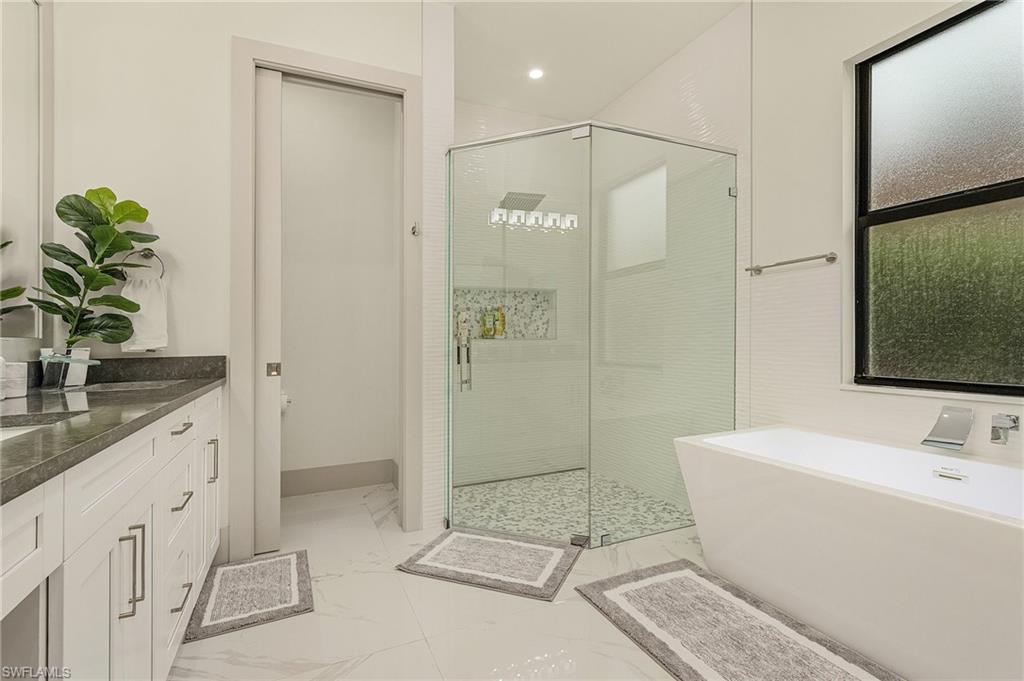 614 105th Avenue North Naples, FL 34108 - Photo 17 of 37 a spacious bathroom with a granite countertop sink a toilet and shower