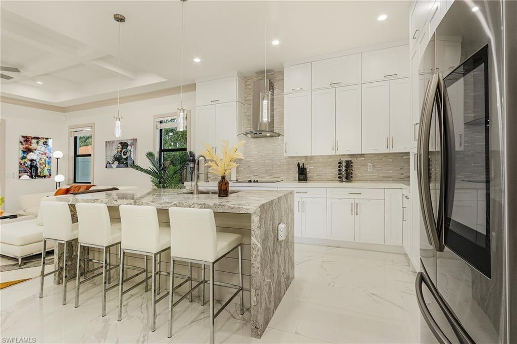 614 105th Avenue North Naples, FL 34108 - Photo 9 of 37 a kitchen with stainless steel appliances kitchen island granite countertop a refrigerator and white cabinets