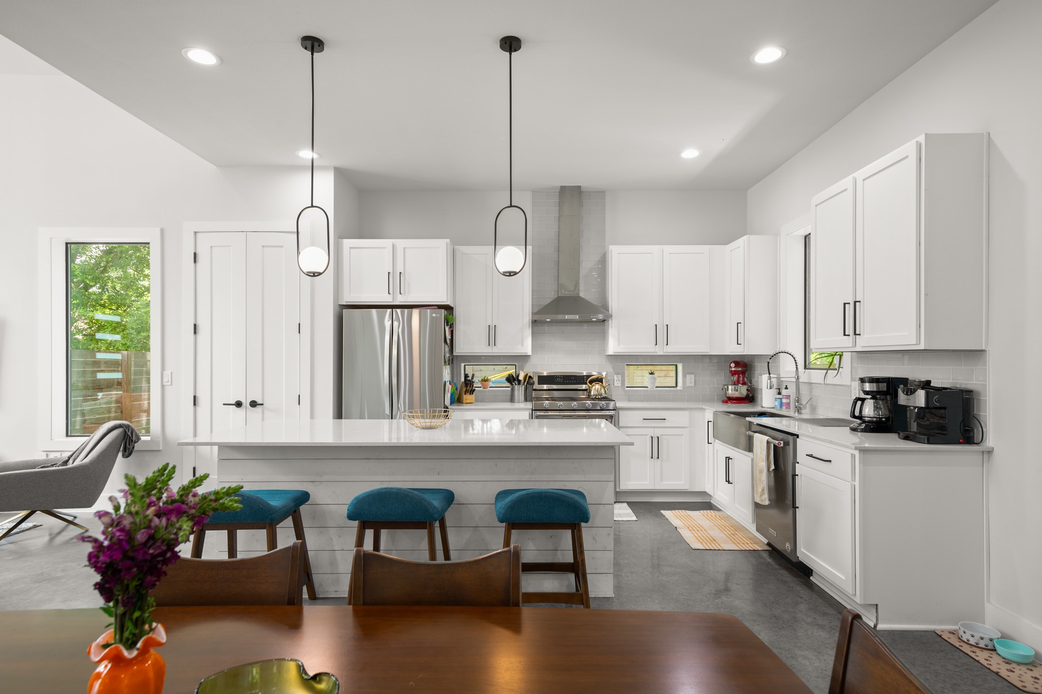 611 Gaylor Street, Unit 2 Austin, TX 78752 - Photo 18 of 31 Kitchen featuring stainless steel appliances, wall chimney range hood, a kitchen breakfast bar, tasteful backsplash, and white cabinetry