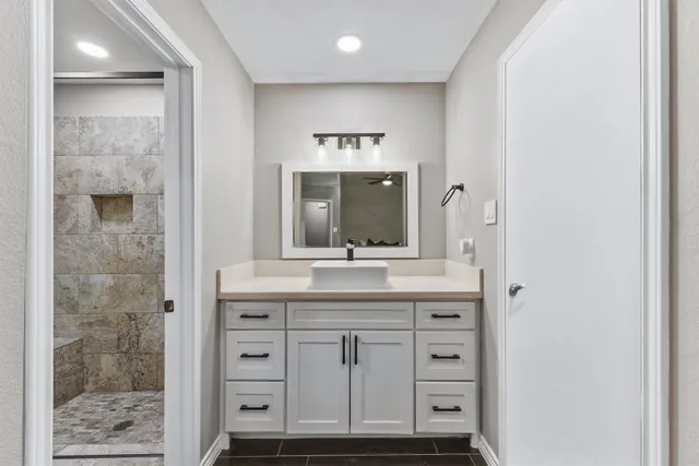 a bathroom with a granite countertop sink a large mirror and a shower