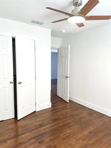 an empty room with wooden floor and a ceiling fan