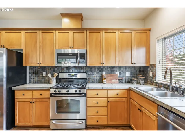 a kitchen with stainless steel appliances granite countertop a stove a sink and a microwave