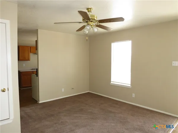 an empty room with a window and a ceiling fan