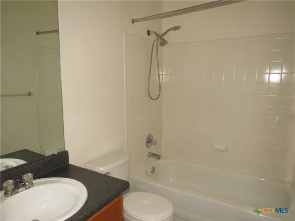 a bathroom with a granite countertop bathtub shower sink vanity and toilet