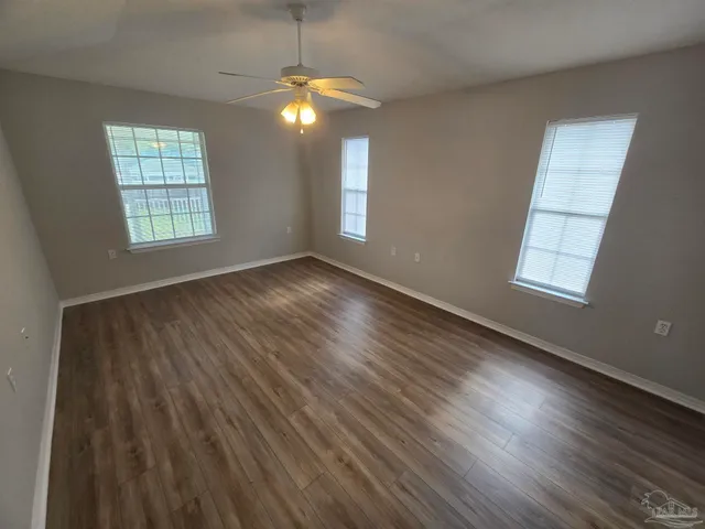 an empty room with wooden floor chandelier and windows