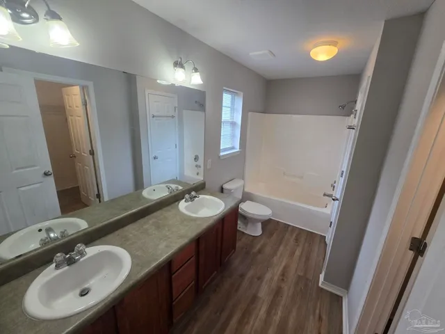 a bathroom with a granite countertop sink a toilet a mirror and shower