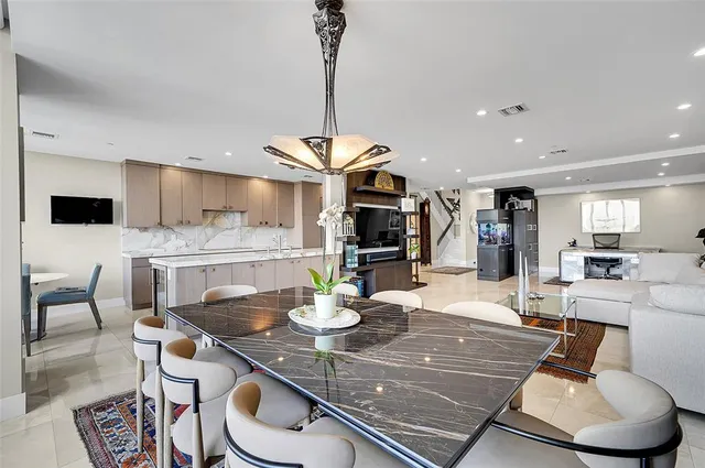 a dining room with stainless steel appliances kitchen island granite countertop a table chairs and a microwave
