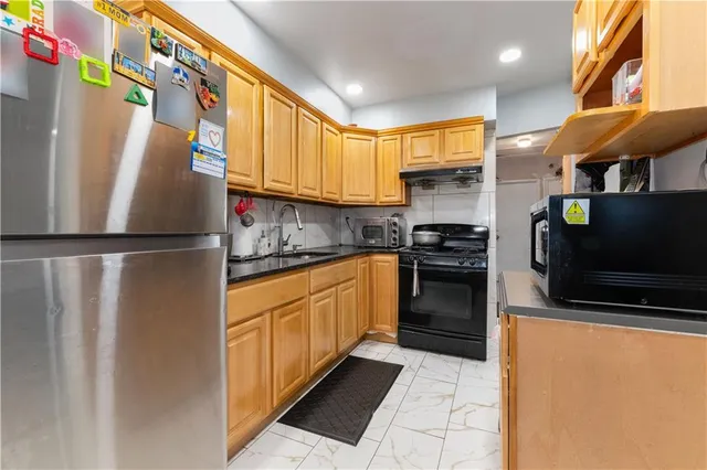 a kitchen with stainless steel appliances granite countertop a refrigerator a stove and a sink