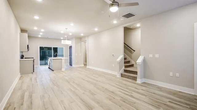 a view of a living room with wooden floor and a kitchen