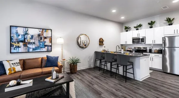 a living room with stainless steel appliances furniture a fireplace a flat screen tv and a window