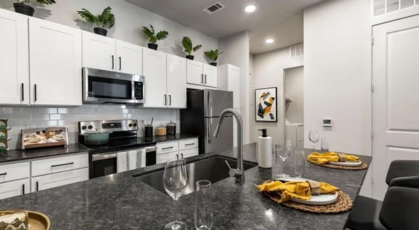 a kitchen with stainless steel appliances granite countertop a sink a stove a refrigerator a microwave a counter top and cabinets