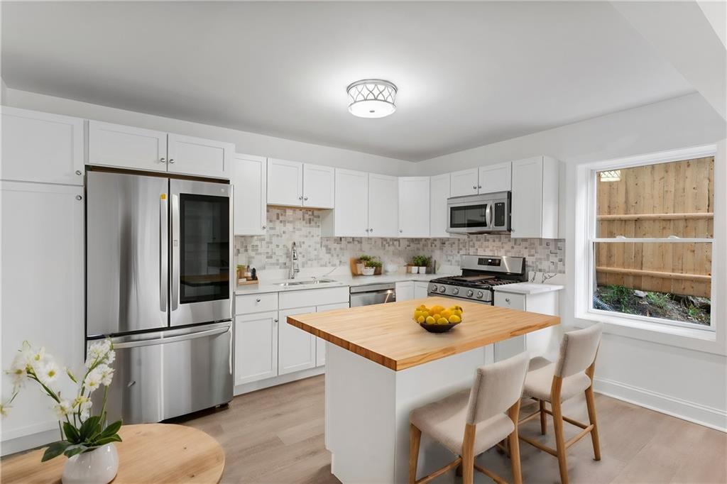 875 Dickson Road Sewickley, PA 15143 - Photo 5 of 29 a kitchen with a refrigerator a stove a sink dishwasher and white cabinets with wooden floor